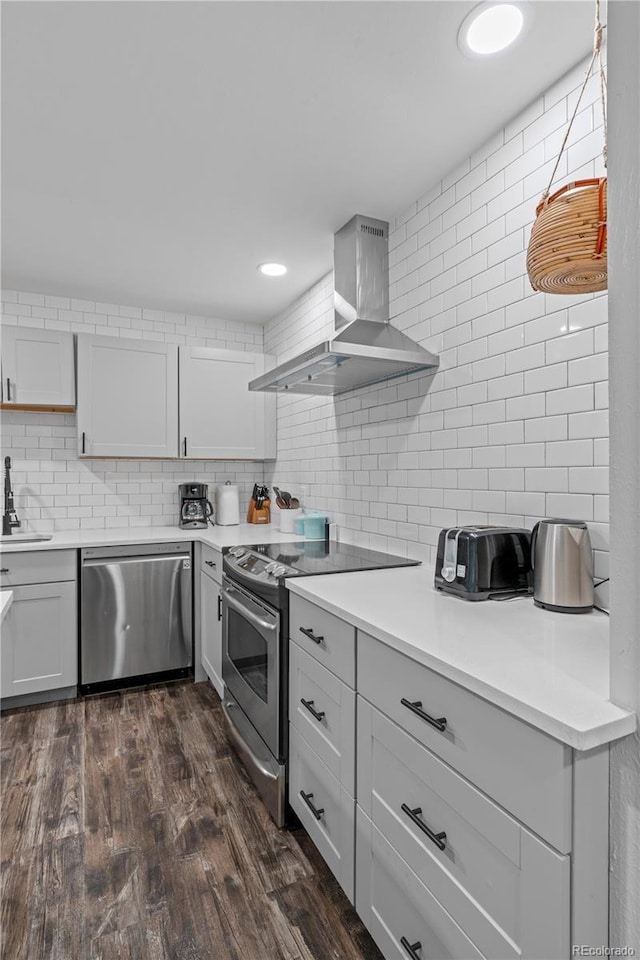 8060 Stuart Pl, Westminster, CO 80031 - kitchen featuring appliances with stainless steel finishes, wall chimney exhaust hood, decorative backsplash, and dark wood-style flooring