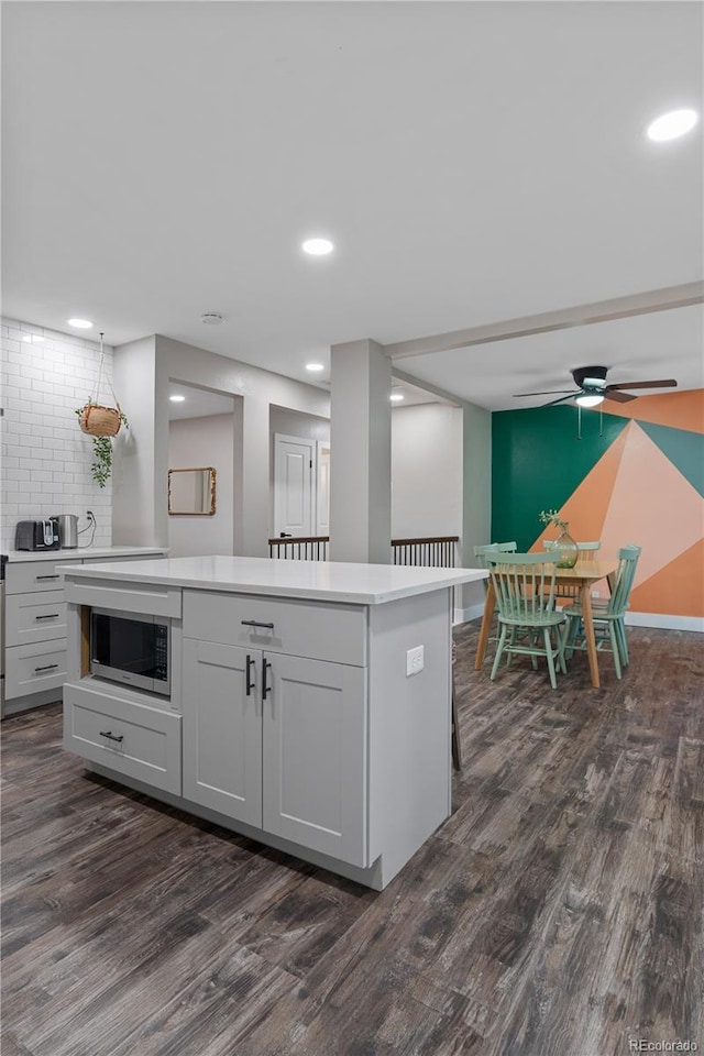 8060 Stuart Pl, Westminster, CO 80031 - kitchen featuring stainless steel microwave, dark wood-style floors, ceiling fan, a center island, and light countertops