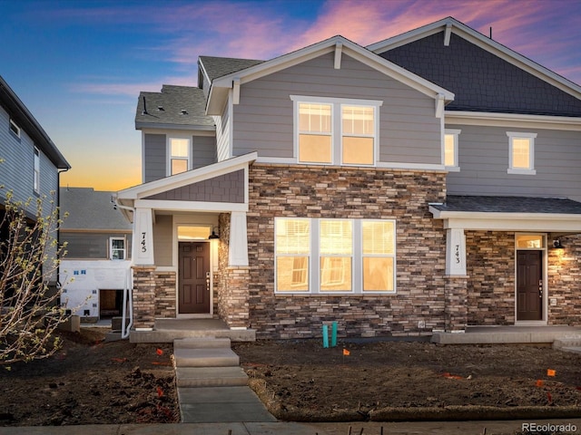 craftsman-style home featuring a shingled roof and stone siding