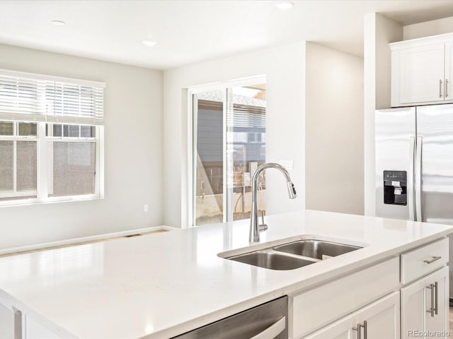 kitchen featuring stainless steel refrigerator with ice dispenser, a sink, a healthy amount of sunlight, and light countertops