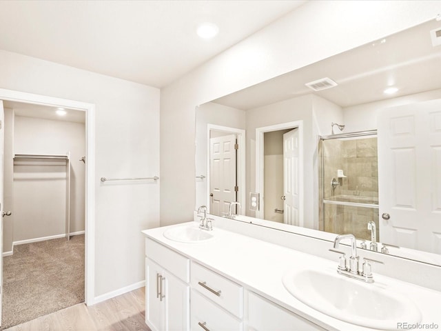 full bathroom featuring visible vents, a shower stall, a sink, and a spacious closet