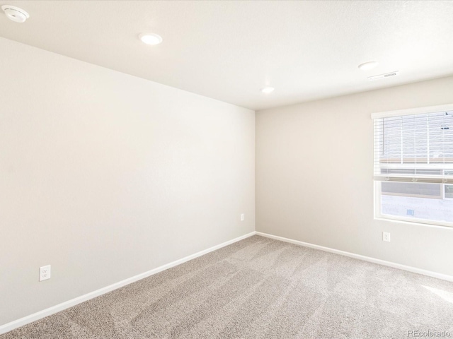 empty room with carpet floors, recessed lighting, baseboards, and visible vents