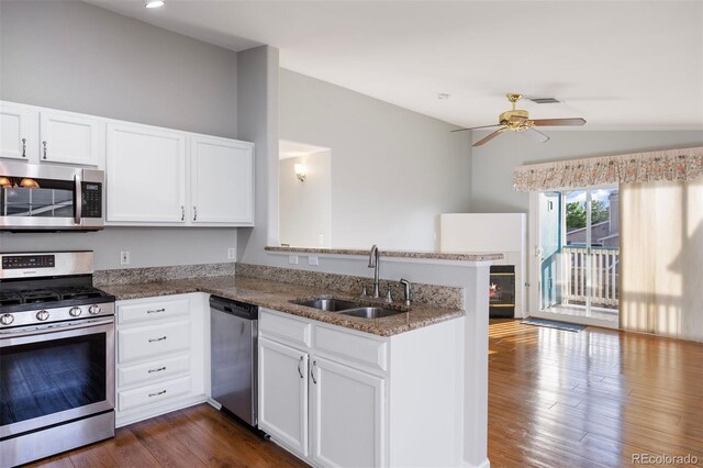 3857 Mossy Rock Dr Unit 201, Highlands Ranch, CO 80126 - kitchen featuring appliances with stainless steel finishes, a peninsula, vaulted ceiling, white cabinetry, and stone countertops