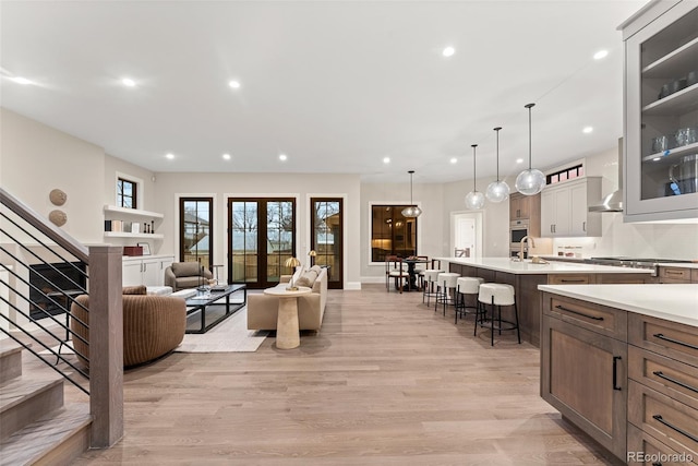 living room with sink, light hardwood / wood-style floors, and french doors