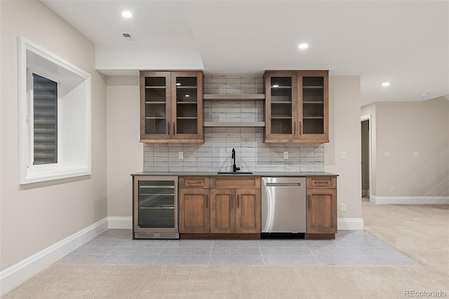 kitchen featuring tasteful backsplash, sink, beverage cooler, stainless steel dishwasher, and light tile patterned floors