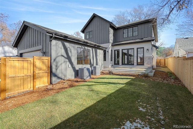 rear view of house with central AC, a patio area, and a lawn