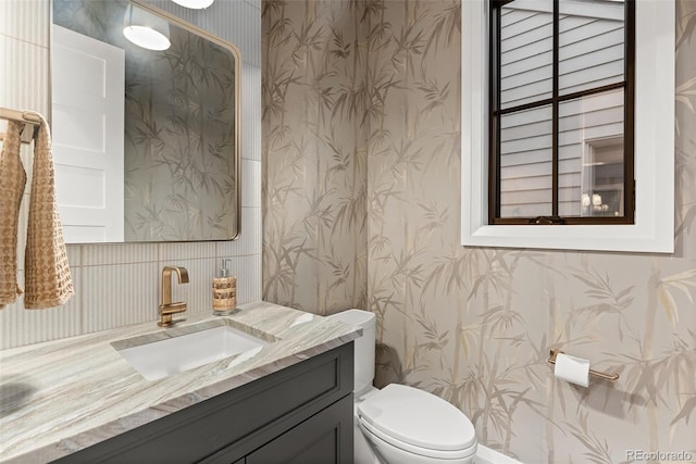bathroom featuring vanity, toilet, and wallpapered walls
