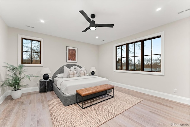 bedroom with visible vents, baseboards, light wood finished floors, and multiple windows