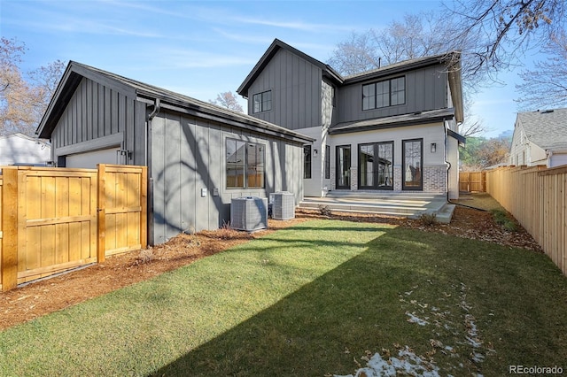 back of property featuring board and batten siding, a fenced backyard, a gate, central air condition unit, and a yard