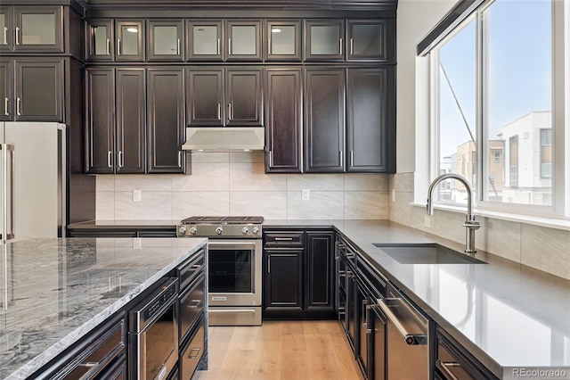 815 Promenade Dr, Superior, CO 80027 - kitchen with appliances with stainless steel finishes, a sink, under cabinet range hood, light stone countertops, and tasteful backsplash