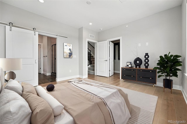 815 Promenade Dr, Superior, CO 80027 - bedroom with a spacious closet, recessed lighting, light wood-type flooring, a barn door, and baseboards