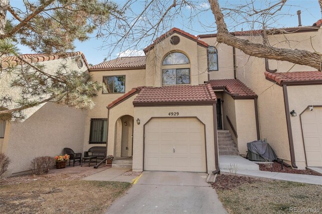 view of front of property with a tile roof, concrete driveway, a garage, and stucco siding