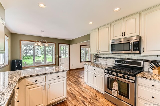 6351 S Andes Pl, Centennial, CO 80016 - kitchen with appliances with stainless steel finishes, a chandelier, light wood finished floors, backsplash, and recessed lighting