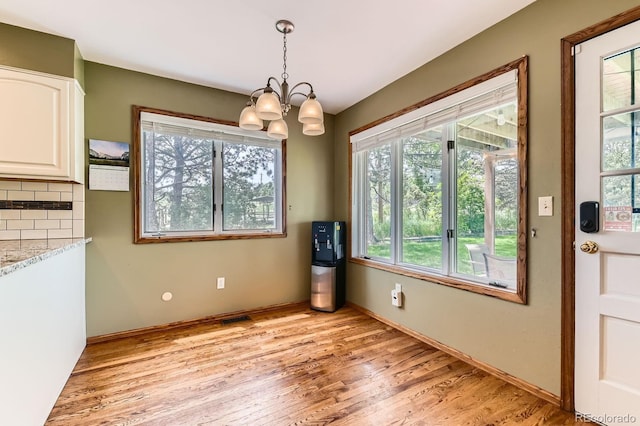 6351 S Andes Pl, Centennial, CO 80016 - unfurnished dining area featuring plenty of natural light, a chandelier, light wood-style flooring, and baseboards