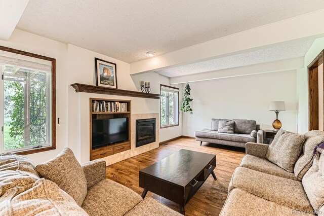 6351 S Andes Pl, Centennial, CO 80016 - living room featuring a tile fireplace, wood finished floors, a textured ceiling, and baseboards