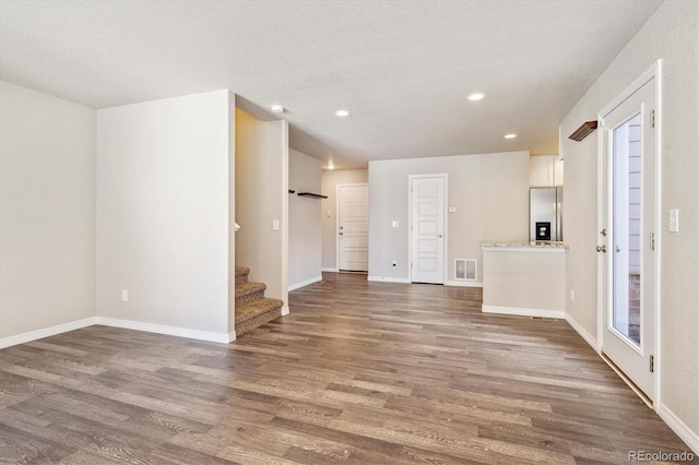 unfurnished living room featuring recessed lighting, visible vents, stairway, wood finished floors, and baseboards