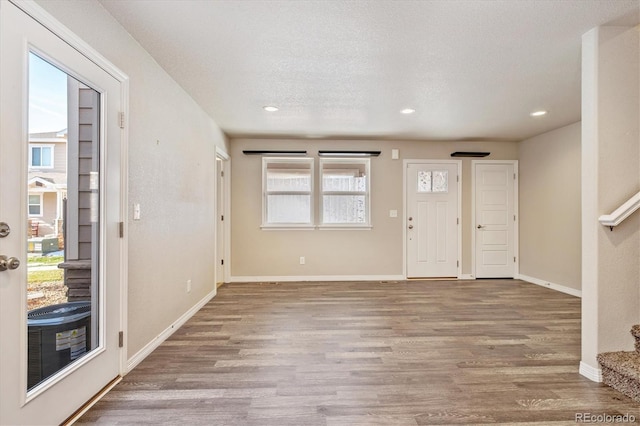 foyer entrance with a textured ceiling, recessed lighting, wood finished floors, baseboards, and stairs