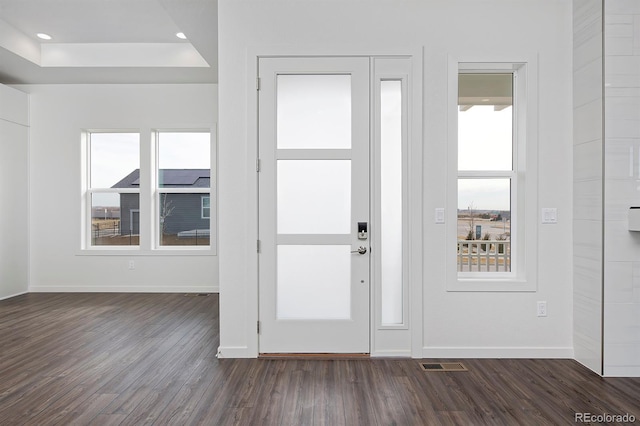 foyer entrance featuring baseboards, visible vents, dark wood finished floors, recessed lighting, and a raised ceiling