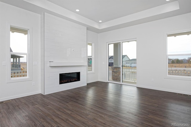 unfurnished living room featuring visible vents, baseboards, a healthy amount of sunlight, and dark wood-style flooring