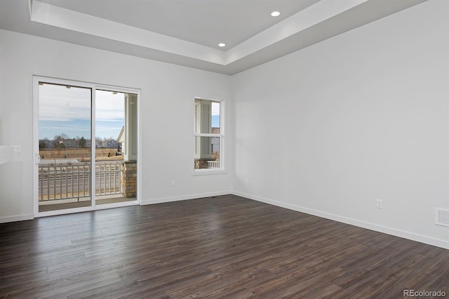 unfurnished room with a raised ceiling, recessed lighting, baseboards, and dark wood-style flooring