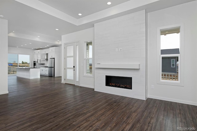 unfurnished living room featuring dark wood-type flooring, recessed lighting, a fireplace, and baseboards