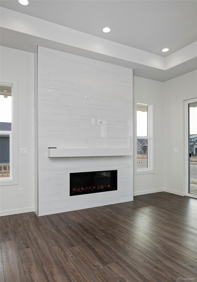 unfurnished living room with dark wood-style floors, baseboards, and a large fireplace