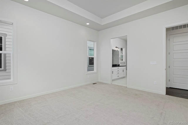 unfurnished bedroom with visible vents, a raised ceiling, recessed lighting, carpet, and baseboards