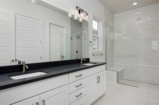 bathroom featuring a tile shower, double vanity, and a sink