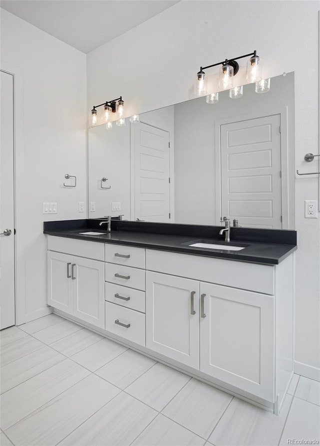 bathroom with double vanity, baseboards, and a sink