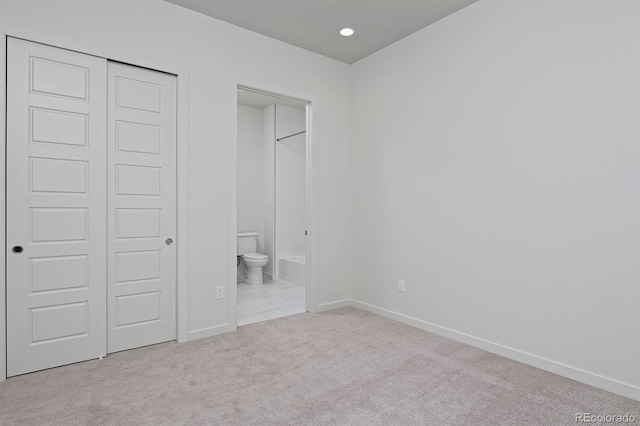 unfurnished bedroom featuring baseboards, carpet floors, recessed lighting, a closet, and ensuite bath