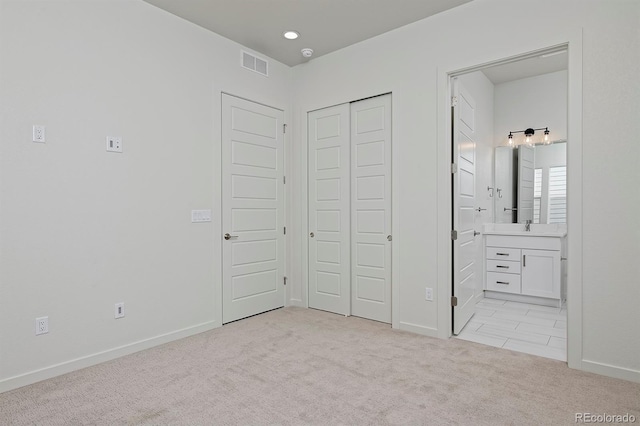 unfurnished bedroom with visible vents, a sink, a closet, baseboards, and light colored carpet