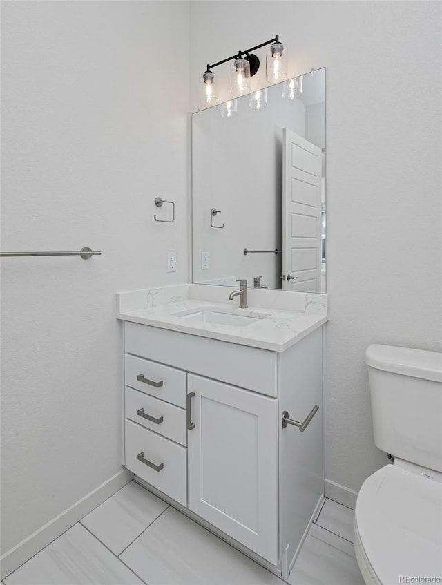 bathroom featuring vanity, toilet, and baseboards