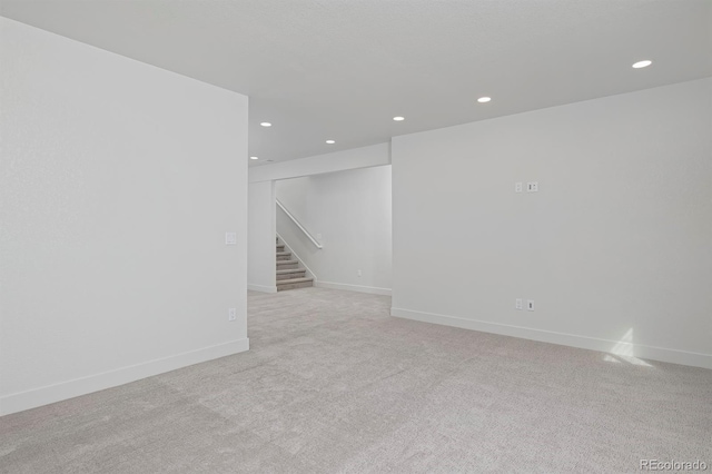 empty room with stairs, recessed lighting, baseboards, and light colored carpet