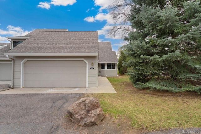 view of front of property featuring roof with shingles, a front yard, a garage, and driveway