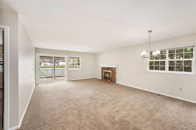 unfurnished living room with carpet, baseboards, a chandelier, and a brick fireplace
