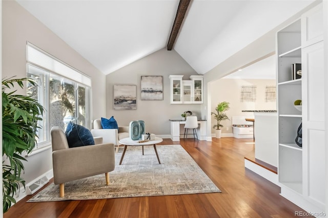 living area featuring wood-type flooring and vaulted ceiling with beams