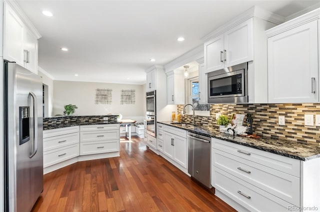 kitchen with sink, stainless steel appliances, dark stone counters, and white cabinets