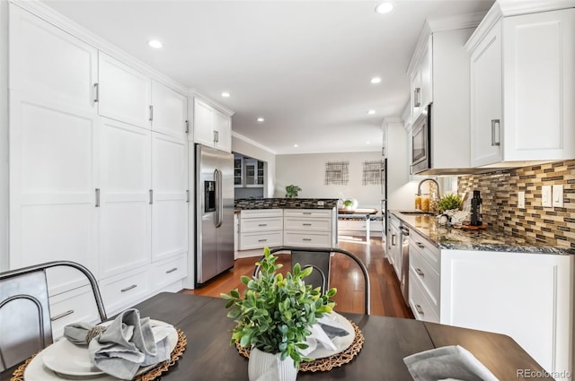 kitchen with white cabinetry, backsplash, dark stone countertops, and appliances with stainless steel finishes