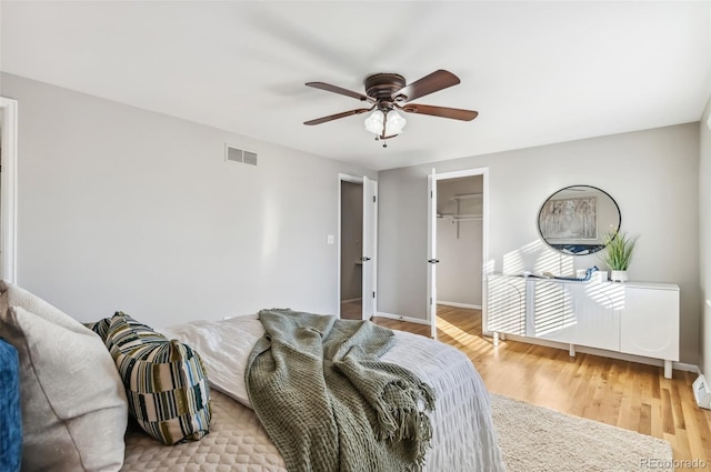 bedroom with ceiling fan, a spacious closet, light hardwood / wood-style floors, and a closet