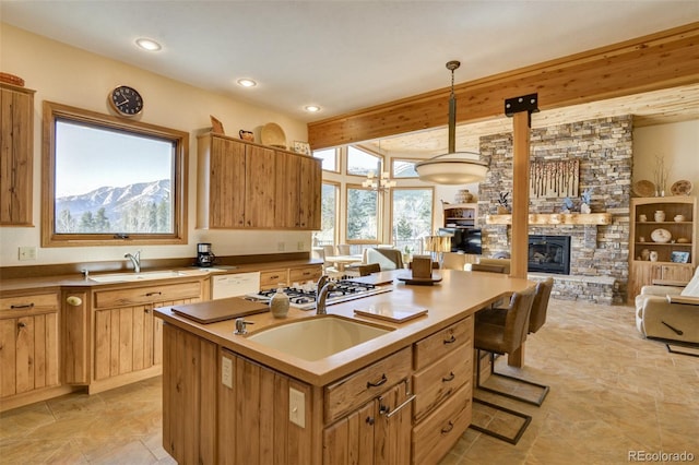 kitchen featuring a stone fireplace, open floor plan, a sink, and beamed ceiling