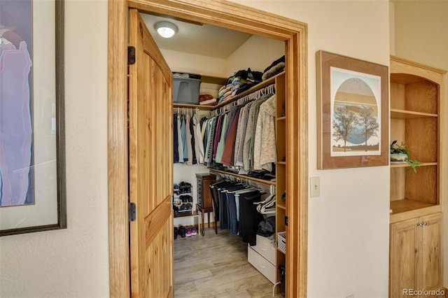 walk in closet with wood finished floors