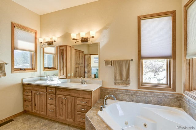 bathroom with a healthy amount of sunlight, a sink, a tub with jets, and double vanity