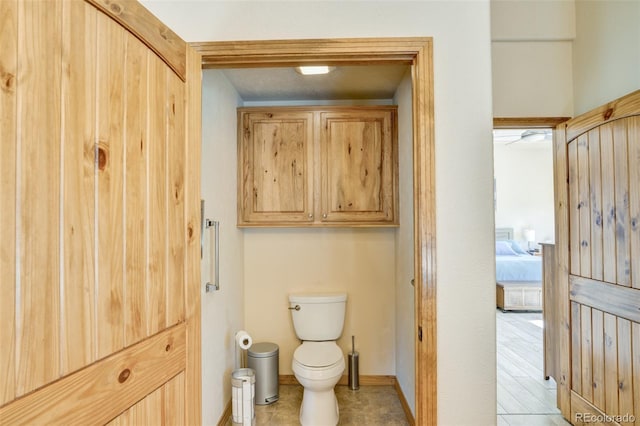 bathroom featuring ensuite bath, toilet, and baseboards