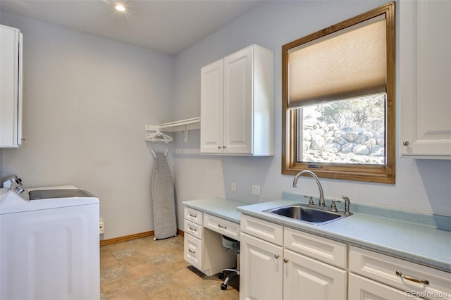 laundry area featuring washer and clothes dryer, a sink, baseboards, cabinet space, and stone finish floor