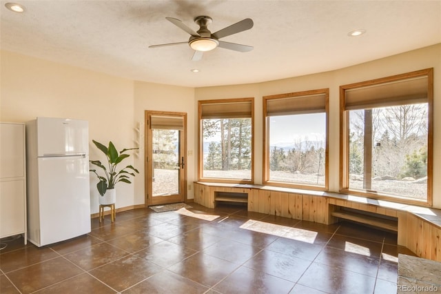 interior space with a textured ceiling, recessed lighting, dark tile patterned flooring, a ceiling fan, and baseboards