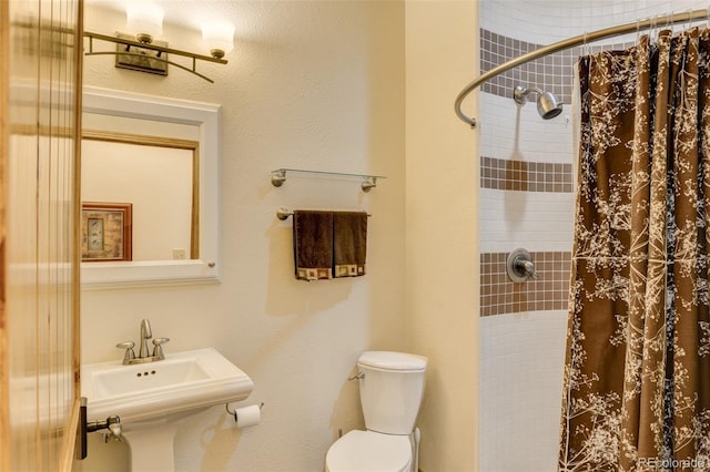 full bath with a sink, a tile shower, and toilet