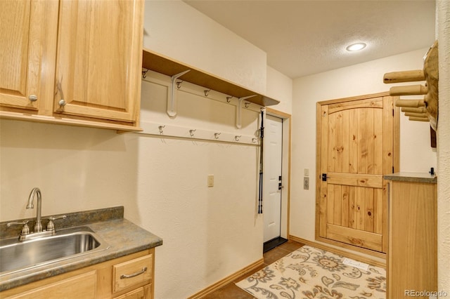 kitchen with a textured ceiling, dark tile patterned flooring, a sink, and light brown cabinetry