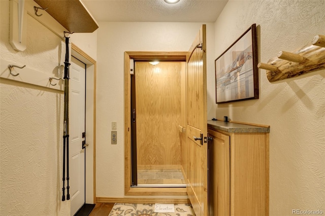 bathroom with a textured ceiling, a textured wall, and elevator