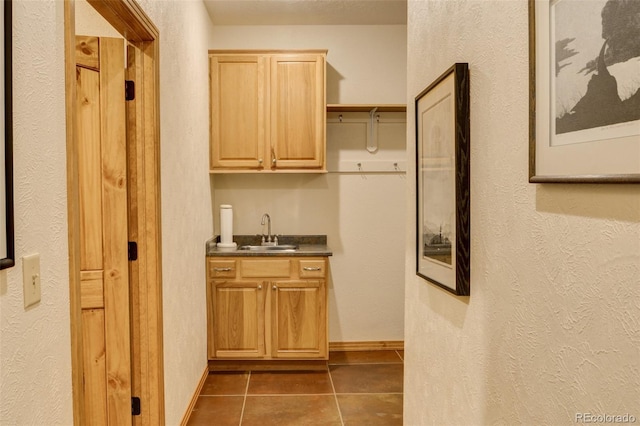 bar with baseboards, a sink, and tile patterned floors