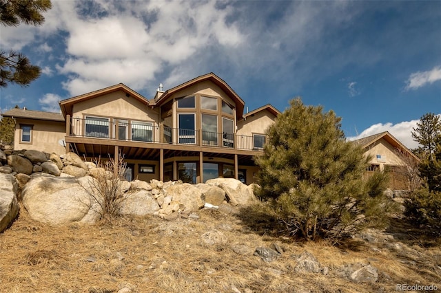 rear view of property featuring a balcony and stucco siding